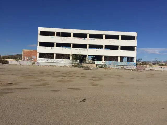 Parcela de terreno asfaltada con construcción, vista desde c