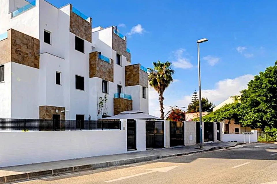 Casa adosada moderna y espaciosa (aprox. 116 m2) con 3 dorm, 3 baños, varias terrazas, y gran piscina comunitaria. Cerca de campos de golf, La Zenia Boulevard, y a poco más de 5 km de las playas.